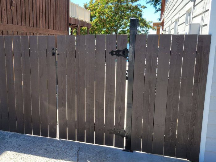 Custom Gate Fabrication A wooden fence with a metal gate in a garden